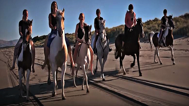 Friends and horses on a summer beach ride